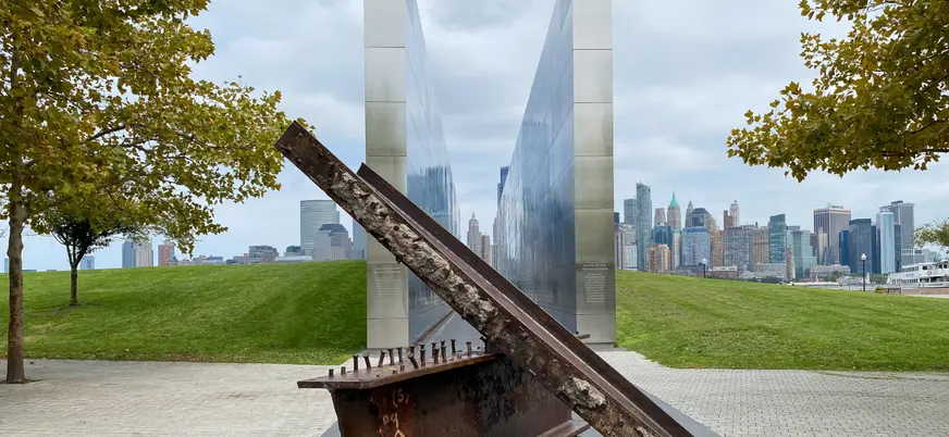 Monumento conmemorativo del 11S con vigas de acero y vista de Manhattan desde Liberty State Park.