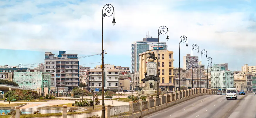 Perspectiva de la Quinta Avenida de La Habana, flanqueada por palmeras y mansiones históricas.