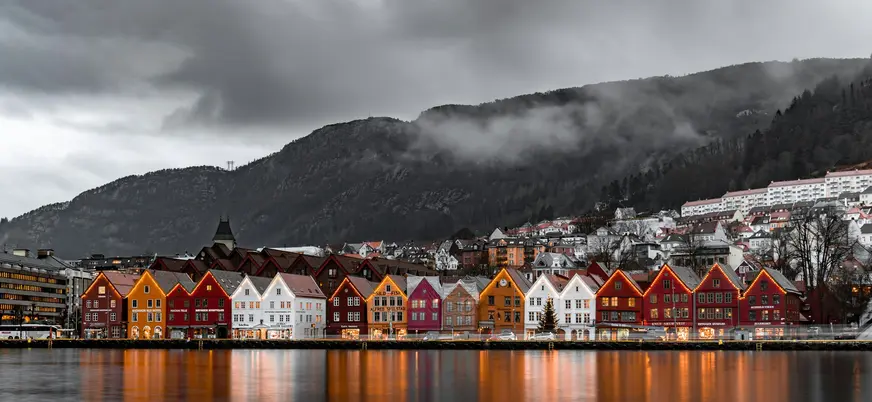 Famoso muelle de Bryggen en Bergen, Noruega, con casas de madera coloridas reflejadas en el agua al anochecer.