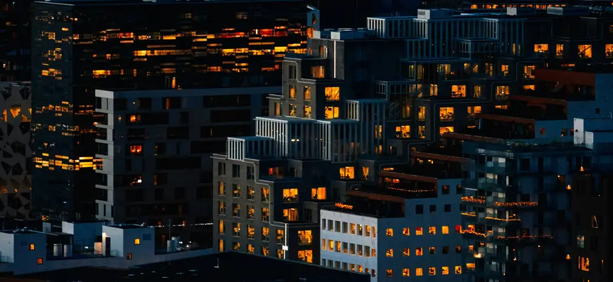 Edificios modernos iluminados al anochecer en el barrio de Bjørvika, Oslo, con arquitectura contemporánea.