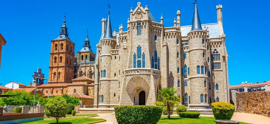 Palacio Episcopal de Astorga, León, diseño neogótico de Gaudí, con torres, jardines y la Catedral al fondo.