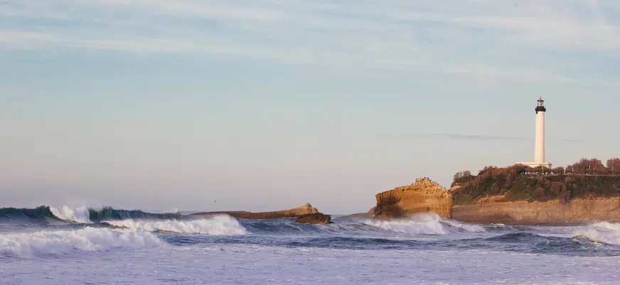 Faro de Biarritz sobre el acantilado con olas rompiendo en la costa.