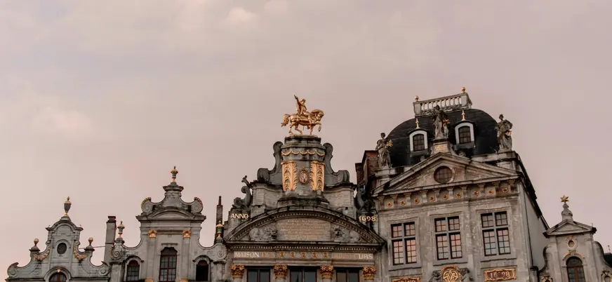 Edificio histórico en la Grand Place de Bruselas con estatua dorada de un caballo en la cima.