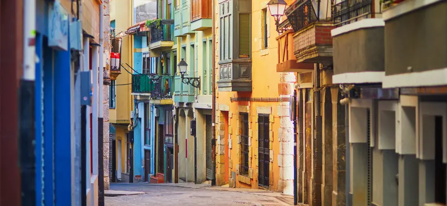 Calle estrecha y colorida de Bermeo, con fachadas tradicionales y balcones en el País Vasco.