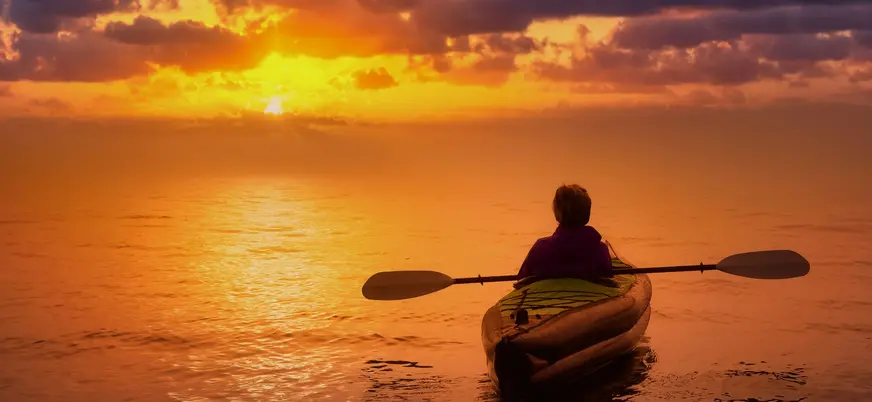 Persona en kayak contemplando un atardecer en Es Grau, Menorca