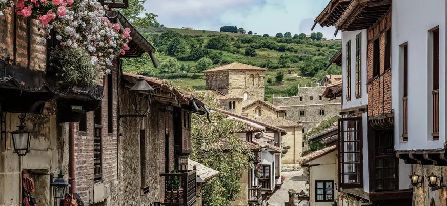 Calle con casas tradicionales y la Colegiata al fondo en Santillana del Mar
