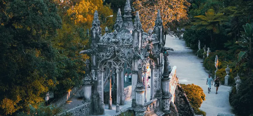 Entrada ornamentada de la Quinta da Regaleira rodeada de jardines y senderos en Sintra.