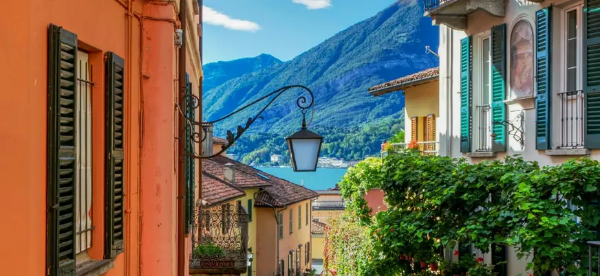Calle colorida con vista al Lago di Como y montañas al fondo