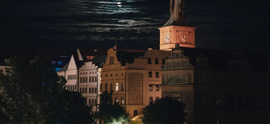 Vista nocturna de edificios históricos bajo la luna en Praga, República Checa