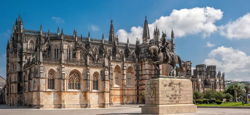 Monasterio de Santa María de la Victoria, Batalha, Portugal, con arquitectura gótica y estatua ecuestre.
