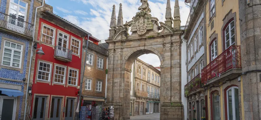 Arco da Porta Nova en Braga rodeado de casas tradicionales y fachadas coloridas.