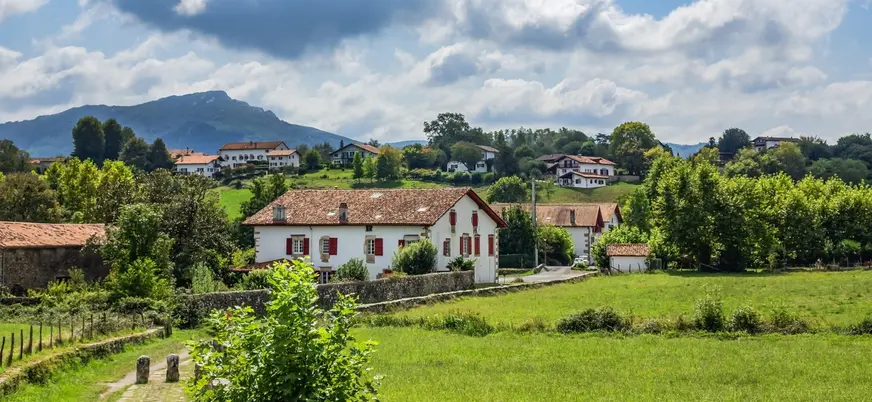 Casas blancas con contraventanas rojas entre prados verdes en Sare, en el País Vasco francés.