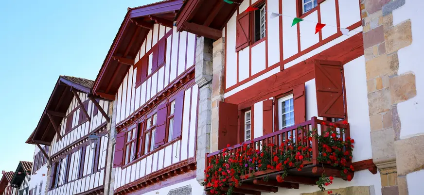 Casas tradicionales con entramado rojo y flores en balcones en Ainhoa, pueblo del País Vasco francés.