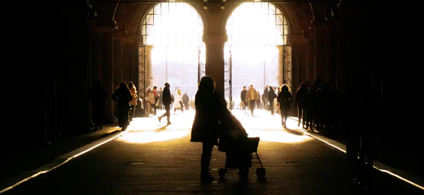 Personas caminando a contraluz por un pasaje iluminado en Ámsterdam