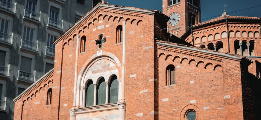 Fachada de la Basílica di San Babila en Milán con ladrillo rojo y campanario