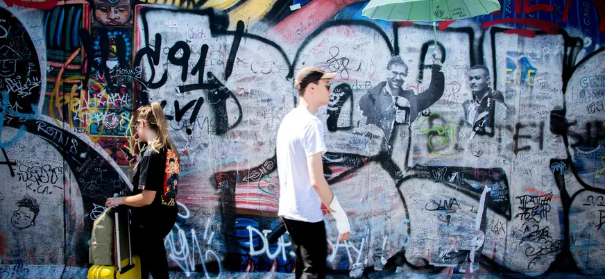 Personas caminando frente a murales coloridos del East Side Gallery en Berlín