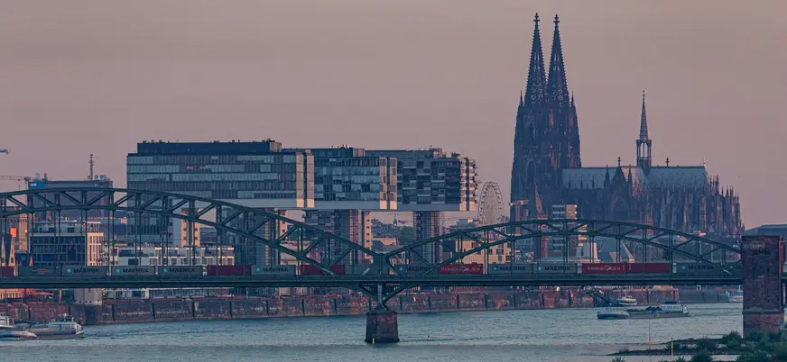 Puente ferroviario y Catedral de Colonia sobre el río Rin al anochecer.