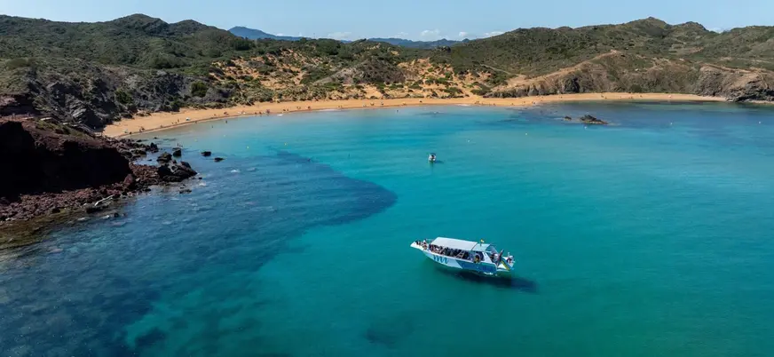 Vista panorámica del barco frente a la playa de Cavalleria, norte de Menorca