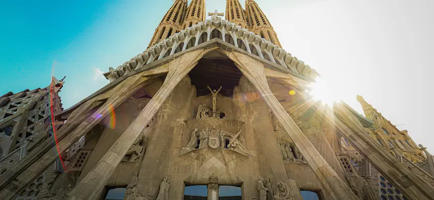 Fachada de la Sagrada Familia en Barcelona iluminada por el sol desde un ángulo bajo