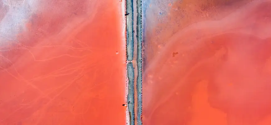 Vista aérea de la Laguna Rosa de Torrevieja con una carretera que divide las intensas aguas rosadas.