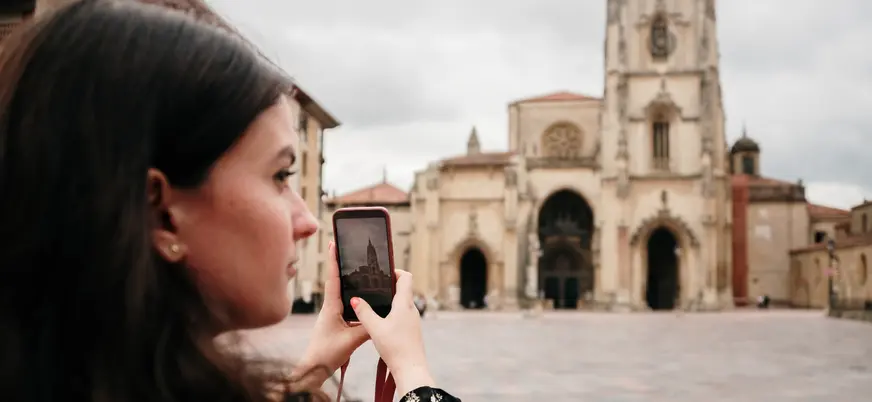 Turista fotografiando la Catedral de San Salvador de Oviedo con su móvil durante una visita al casco histórico de la ciudad.