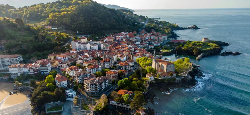 Vista aérea de Mundaka entre el mar Cantábrico y colinas verdes con su casco histórico.