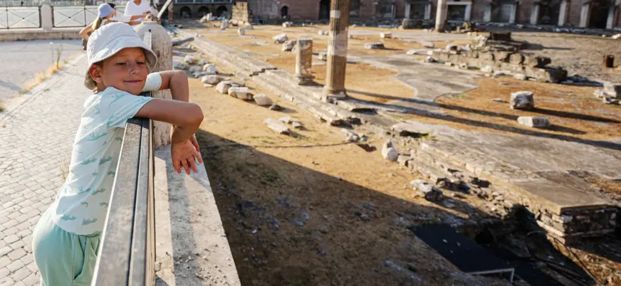 Niño observando las ruinas del Foro Romano desde una barandilla en Roma