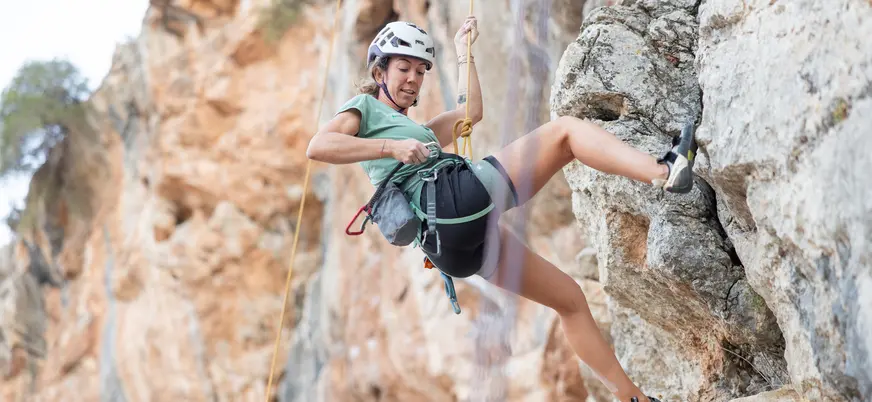 Escaladora realizando un descenso en rappel por una pared de roca en El Chorro
