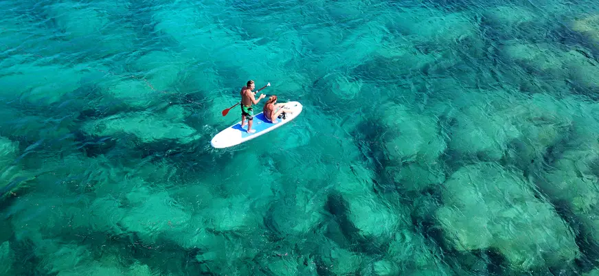 Pareja practicando paddle surf en las aguas de una cala de Mallorca