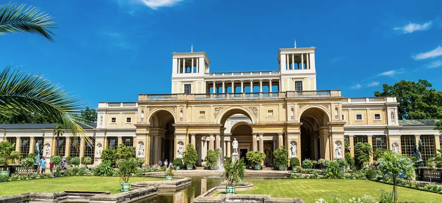 Jardines y fachada principal del Palacio de Orangerie en Potsdam bajo un cielo azul
