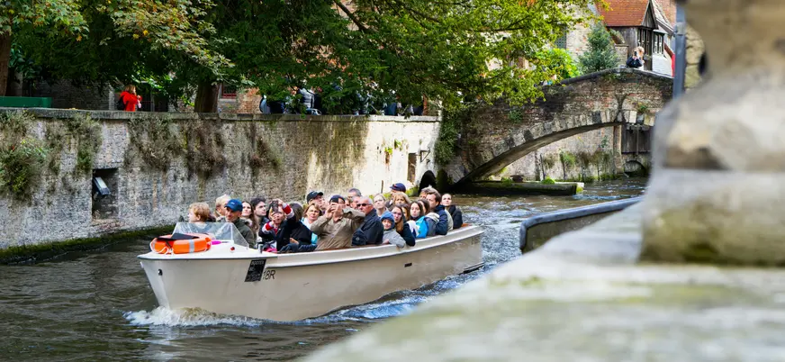 Turistas disfrutando de un paseo en barco por los canales de Brujas, Bélgica