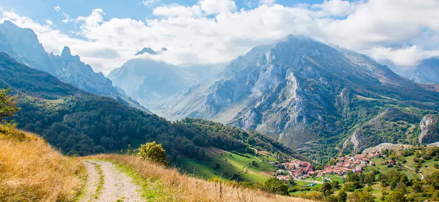 Sendero con vistas a un pueblo y los Picos de Europa