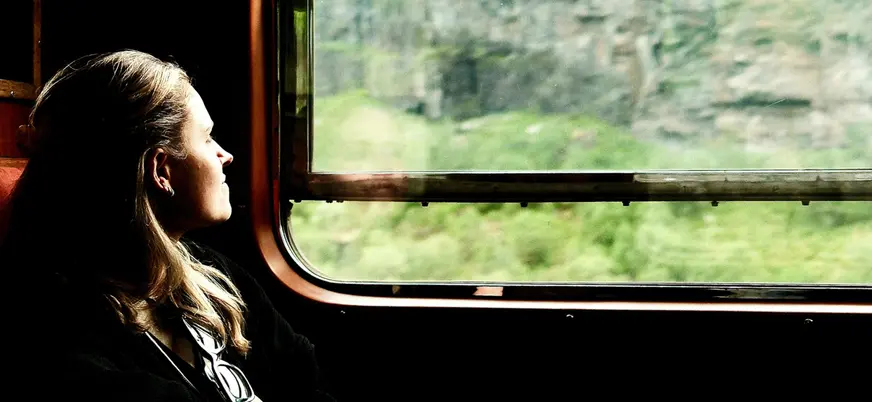 Mujer disfrutando de las vistas por la ventana del tren entre Oslo y Bergen, la famosa línea ferroviaria de Noruega.
