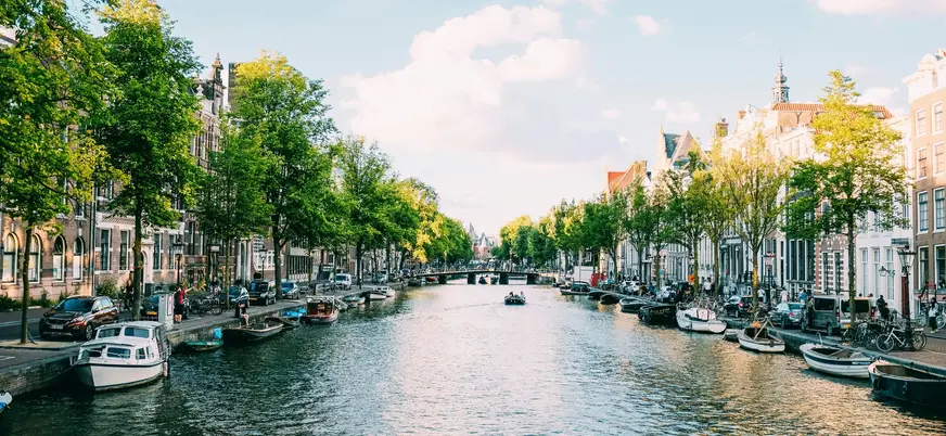 Canal de Ámsterdam rodeado de árboles y edificios típicos.