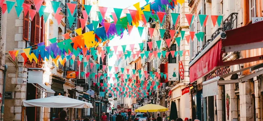 Calle de Bayona decorada con banderines de colores durante ambiente festivo.