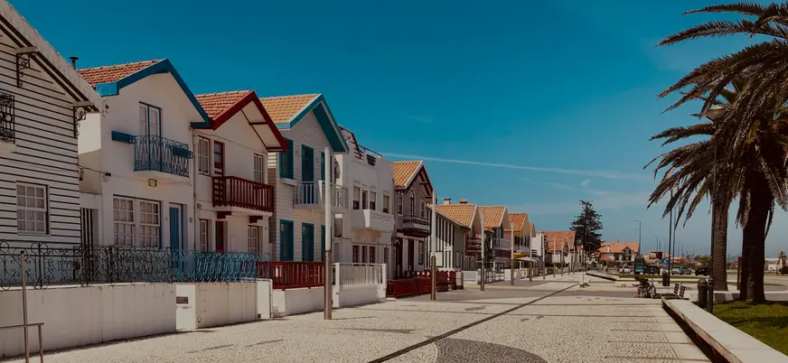Casas de rayas típicas de Costa Nova junto al paseo marítimo en un día soleado.