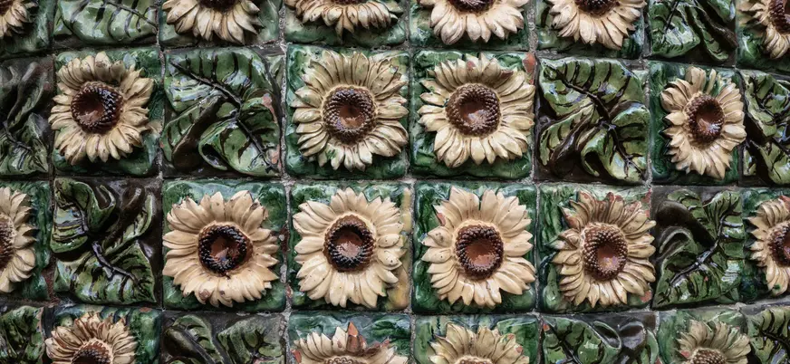Azulejos cerámicos con girasoles en relieve y fondo verde.