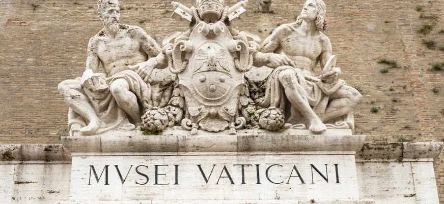 Entrada de los Museos Vaticanos con esculturas y el emblema papal en la Ciudad del Vaticano.