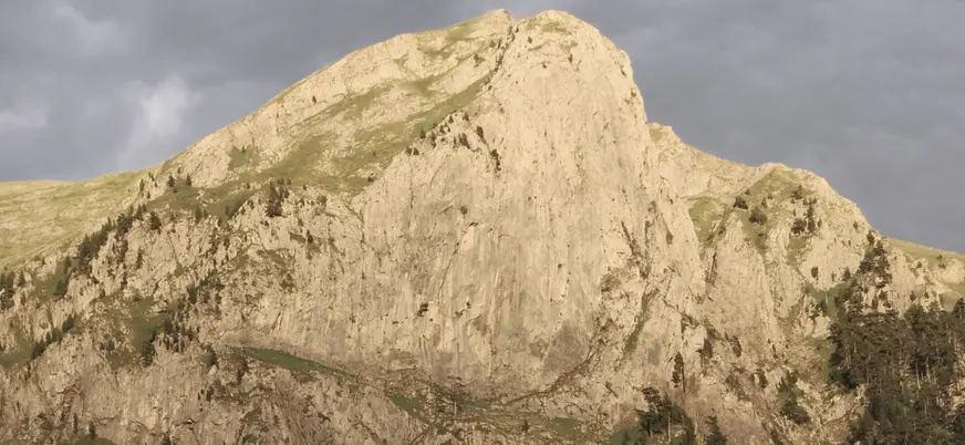 Pico de la Peña Oroel, un macizo rocoso y escarpado en los Pirineos cerca de Jaca, bajo un cielo nublado y oscuro.