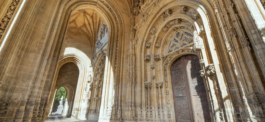 Detalle del pórtico gótico de la Catedral de Oviedo, con sus arcos ornamentados y puerta tallada, joya del arte asturiano.