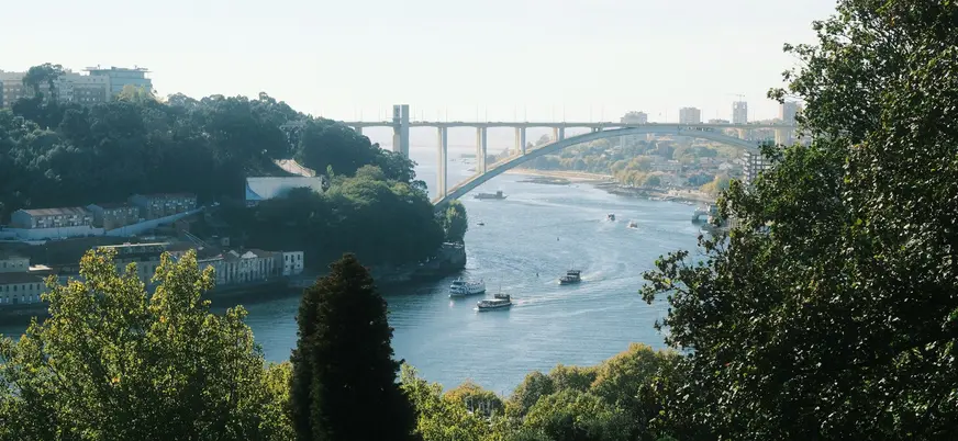 Puente de Arrábida sobre el río Duero con barcos y vegetación en Oporto.