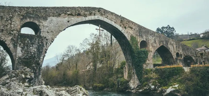 Puente Romano de Cangas de Onís en Asturias, con la emblemática Cruz de la Victoria colgando sobre el río Sella.