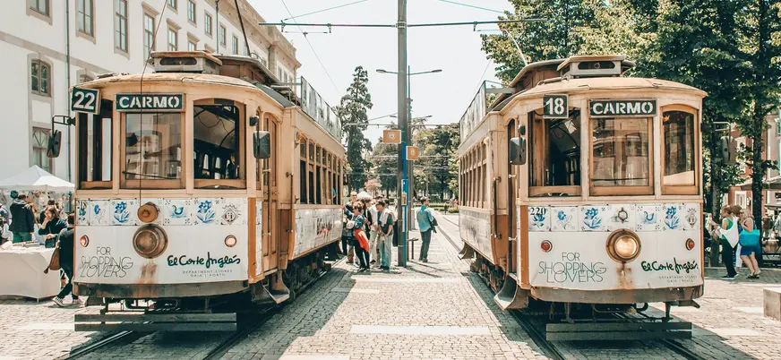 Dos tranvías históricos de Oporto en la línea de Carmo con gente a su alrededor.