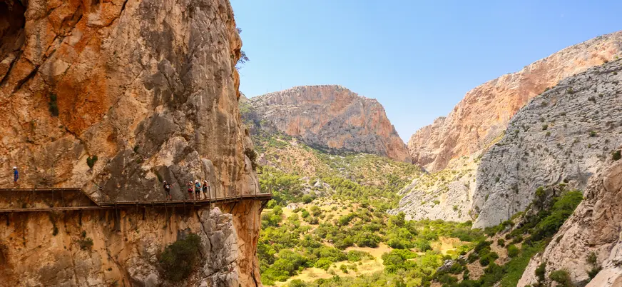 Senderistas recorriendo la pasarela del Caminito del Rey frente al valle