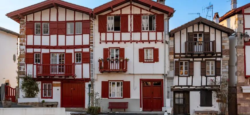 Casas tradicionales con entramado de madera y contraventanas rojas en el centro de Ainhoa.