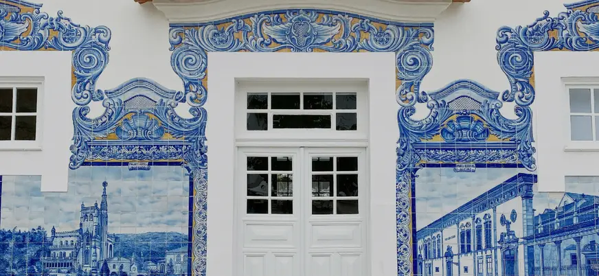 Fachada con azulejos azules decorativos de Aveiro alrededor de una puerta blanca.