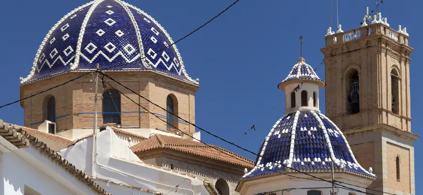 Cúpulas azules y campanario de la iglesia de Altea bajo un cielo despejado.