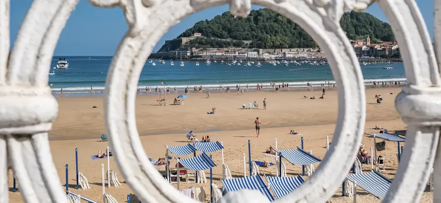 Vista de la playa de La Concha en San Sebastián enmarcada por la barandilla blanca.