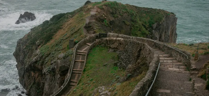 Camino de piedra hacia el mirador de San Juan de Gaztelugatxe junto al mar.