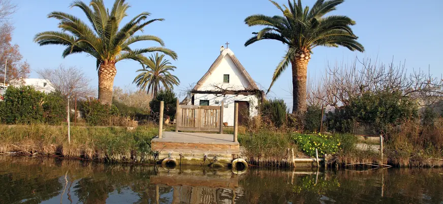 Barraca valenciana tradicional entre palmeras a orillas de la Albufera de Valencia